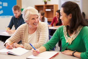 Teacher and student sit together at an adult education class | MiddleWeb